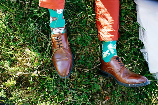 Die Füße des Mannes in Lederschuhen und grünen Socken liegen über dem Rasen