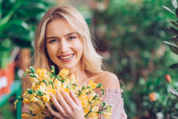 Die glückliche Frau, die mit gelbem steht, blüht Blumenstrauß