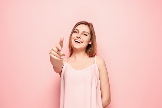 Die glückliche Frau zeigt Sie und will Sie, halbes Länge Nahaufnahmeporträt auf rosa Wand