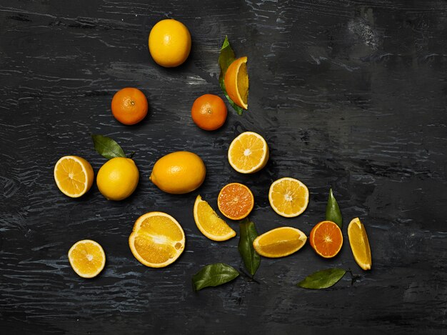 Die Gruppe der frischen Früchte - Zitronen und Mandarinen gegen den schwarzen Raum