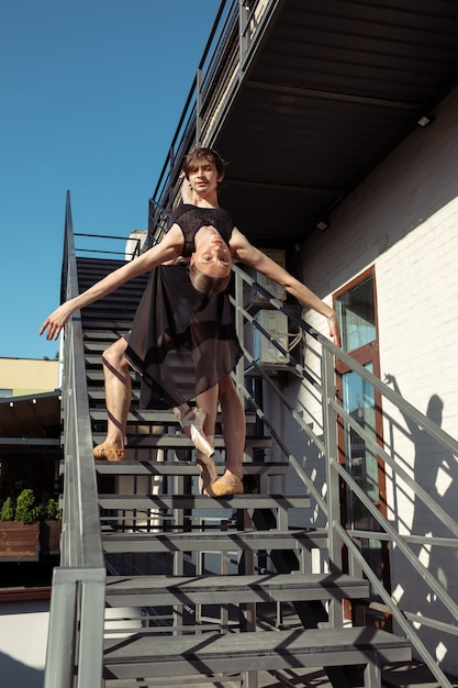 Die Gruppe der modernen Balletttänzer, die auf der Treppe in der Stadt auftreten