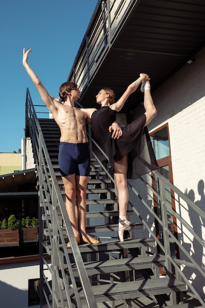 Die Gruppe der modernen Balletttänzer, die auf der Treppe in der Stadt auftreten