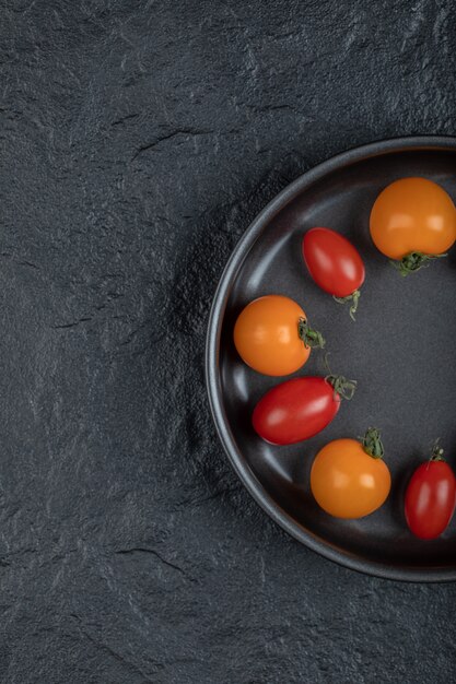 Die Hälfte der bunten Kirschtomaten in der Pfanne auf schwarzem Hintergrund. Hochwertiges Foto