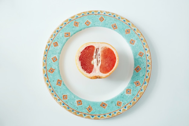 Kostenloses Foto die hälfte der grapefruit auf dem teller. von oben. gesundes fitness-essen.