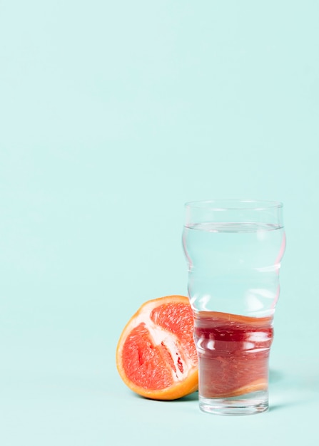 Kostenloses Foto die hälfte der grapefruit mit einem glas wasser