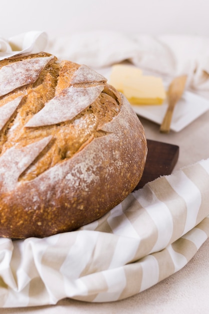 Die Hälfte des runden Brotes auf einem Tuch und verschwommener Butter