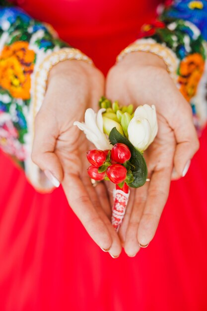 Die Hände der Braut halten den Boutonniere ihres Bräutigams