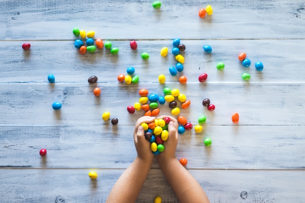 Die Hände eines Kindes halten einen Stapel bunter Süßigkeiten