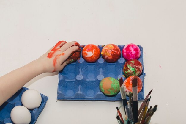 Die Hand der Ernte, die farbige Eier berührt