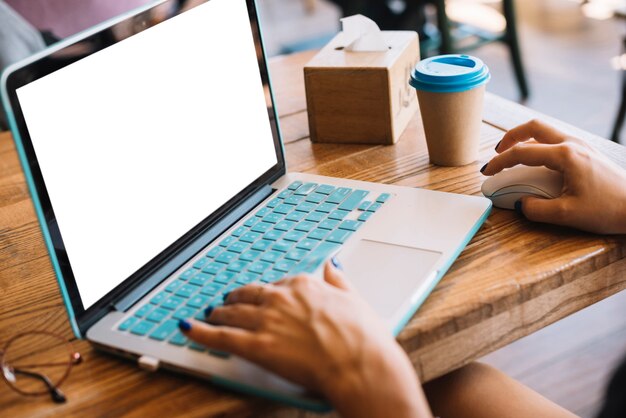 Die Hand der Frau, die auf dem Laptop im Café schreibt