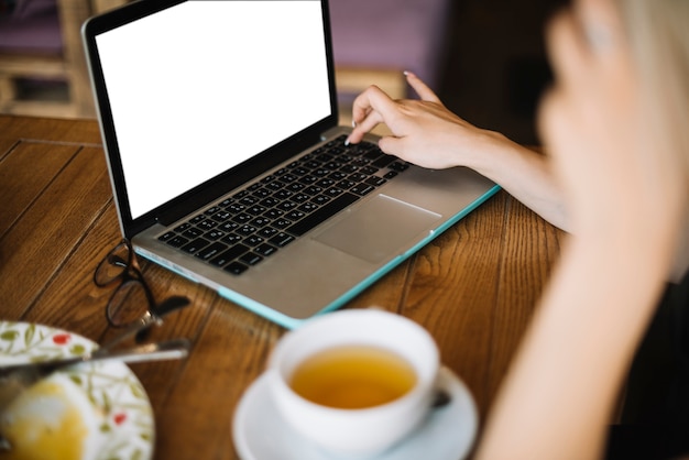 Die Hand der Frau, die auf dem Laptop im Café schreibt