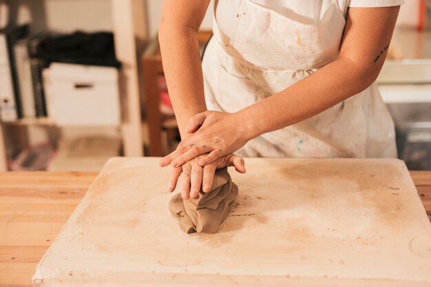 Die Hand der Frau, die auf dem Tisch einen Lehm knetet