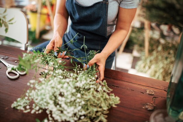 Die Hand der Frau, die Blumenanlagen auf hölzernem Schreibtisch sortiert