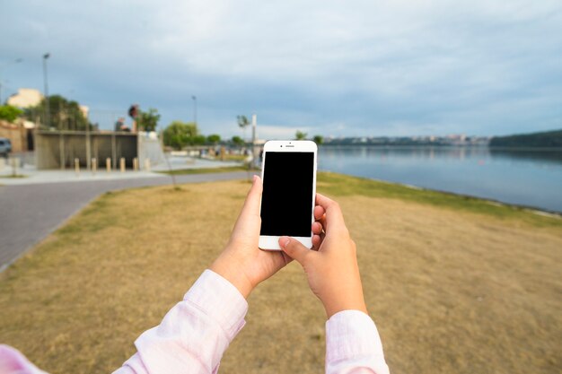 Die Hand der Frau, die draußen Mobiltelefon hält