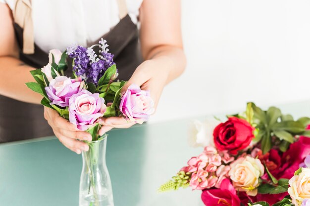 Die Hand der Frau, die frische Blumen im Vase vereinbart