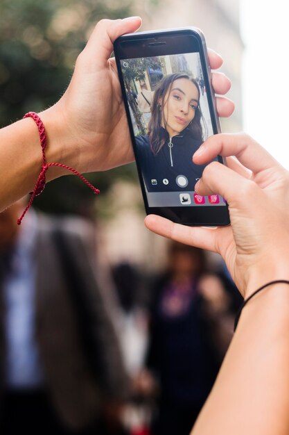 Die Hand der Frau, die Selbstporträt mit intelligentem Telefon nimmt