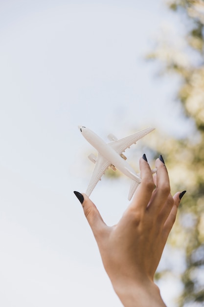 Die Hand der Frau, die weißes Miniaturflugzeug hält