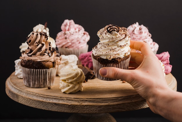 Die Hand der Person, die einen kleinen Kuchen auf Kuchenstand vorwählt