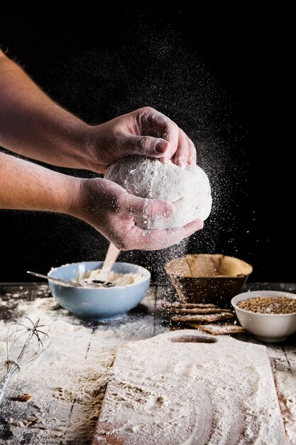 Die Hand des männlichen Bäckers, die Teig für Brot vorbereitet