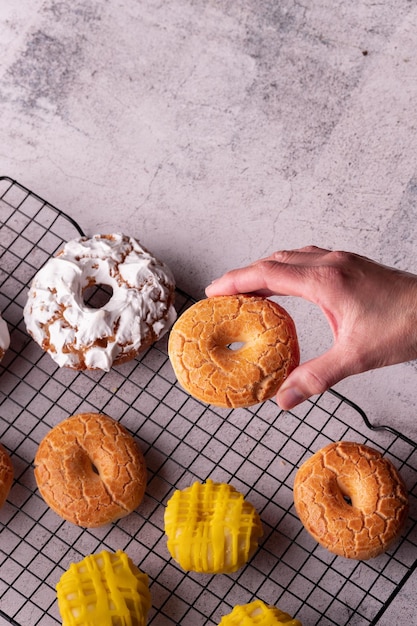 Die Hand des Mannes hält einen köstlichen Donut in der Bäckerei voller glasierter Donuts von San Isidro