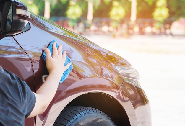 Die Hand des Mannes reinigt und wächst das Auto