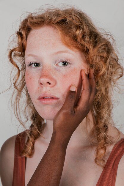 Die Hand einer afrikanischen Frau, welche die Backen ihrer blonden Freundin berührt