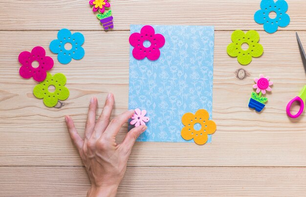 Die Hand einer Person, die Blumenflecken auf Einklebebuchkarte haftet