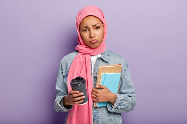 Die horizontale Aufnahme einer traurigen arabischen Frau fühlt sich nach langen Stunden des Studiums unzufrieden und müde