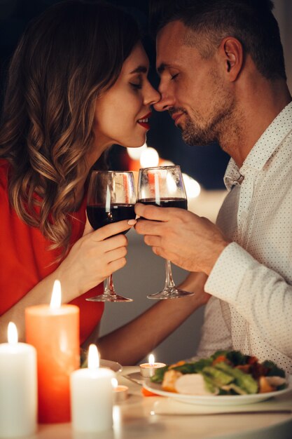 Die junge Dame küsst ihren wunderschönen Mann beim romantischen Abendessen