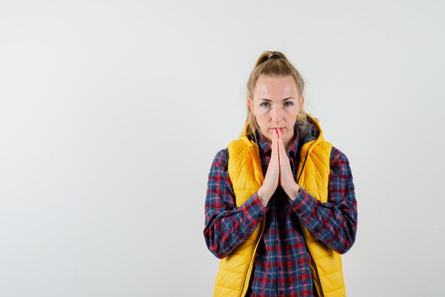 Die junge Frau betet, indem sie die Hände auf weißem Hintergrund zusammenhält