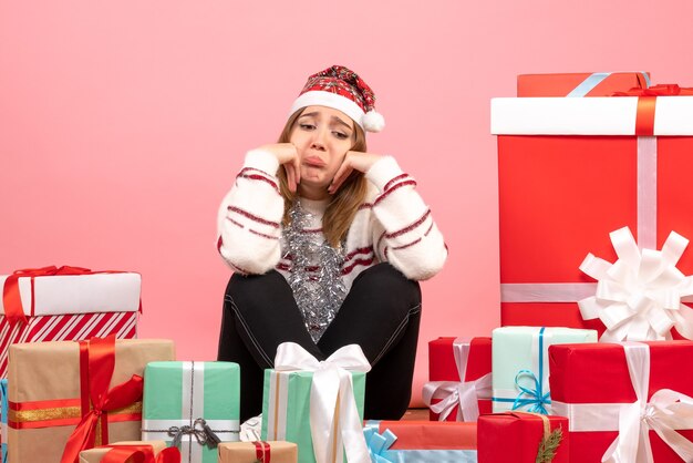 Die junge Frau der Vorderansicht, die um Weihnachten sitzt, präsentiert traurig