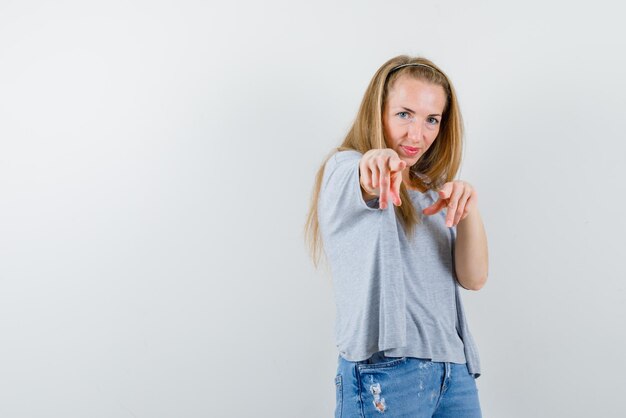 Die junge Frau zeigt auf die Kamera auf weißem Hintergrund