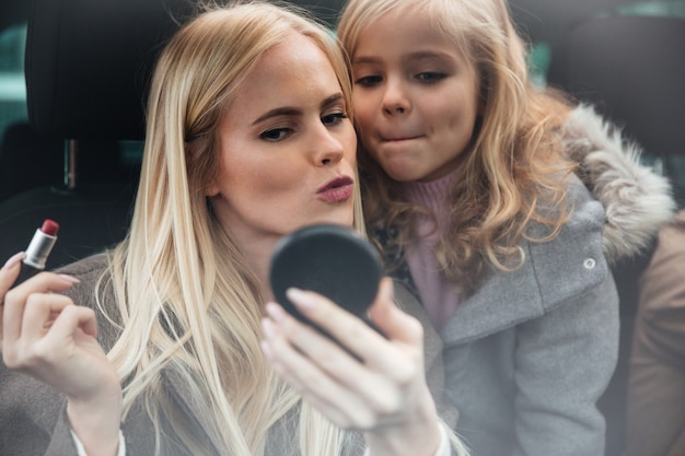 Kostenloses Foto die junge hübsche frau, die make-up tut, betrachten spiegel