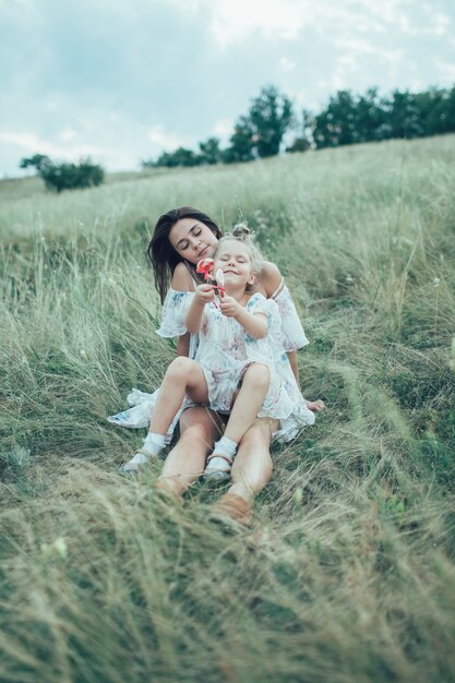 Die junge Mutter und Tochter auf grünem Gras
