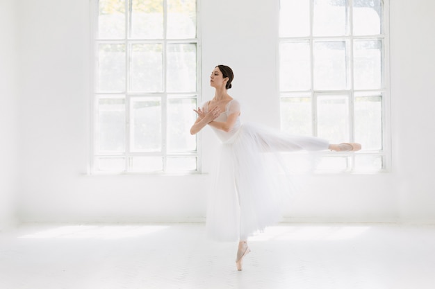 Die junge und unglaublich schöne Ballerina posiert und tanzt in einem weißen Studio