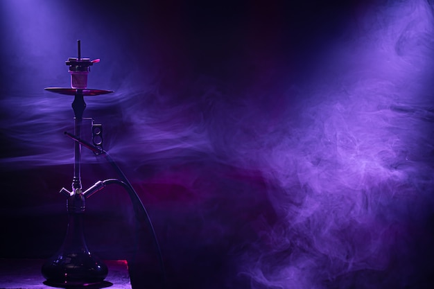 Die klassische Wasserpfeife. Schöne farbige Licht- und Rauchstrahlen. Das Konzept des Shisha-Rauchens.