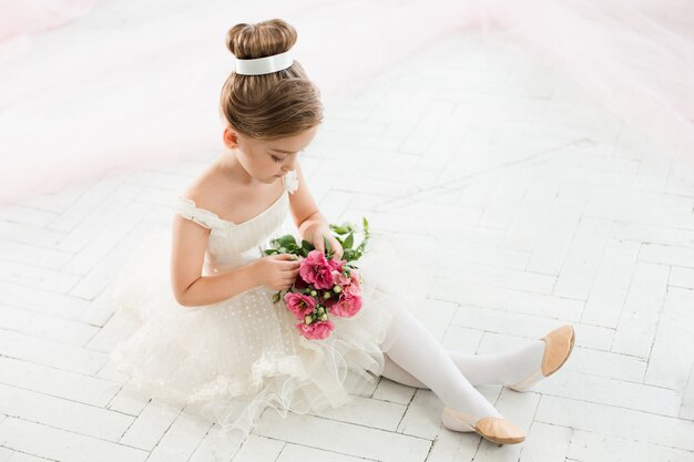 Die kleine Ballenpresse in weißem Tutu im Unterricht beim Ballett