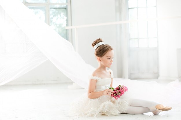 Die kleine Ballenpresse in weißem Tutu im Unterricht in der Ballettschule