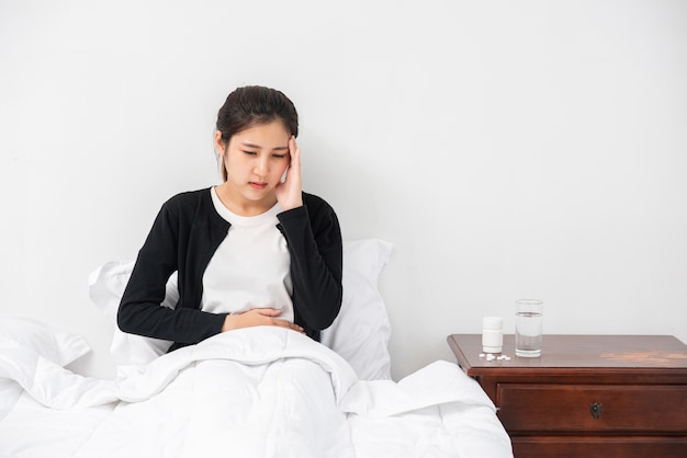 Die kranke Frau hatte Kopfschmerzen und die Hände berührten ihren Kopf auf dem Bett.