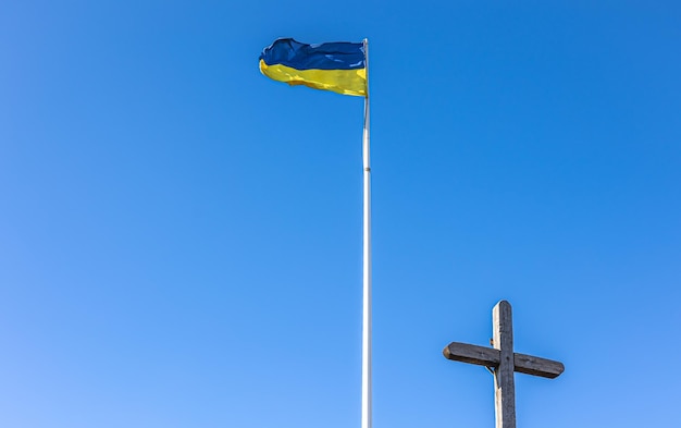 Die Kreuzigung von Jesus Christus und die Flagge der Ukraine gegen den blauen Himmel