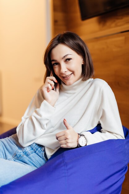 Die kurzhaarige Brünette führt ein nettes Gespräch am Telefon in einer blauen Stuhltasche