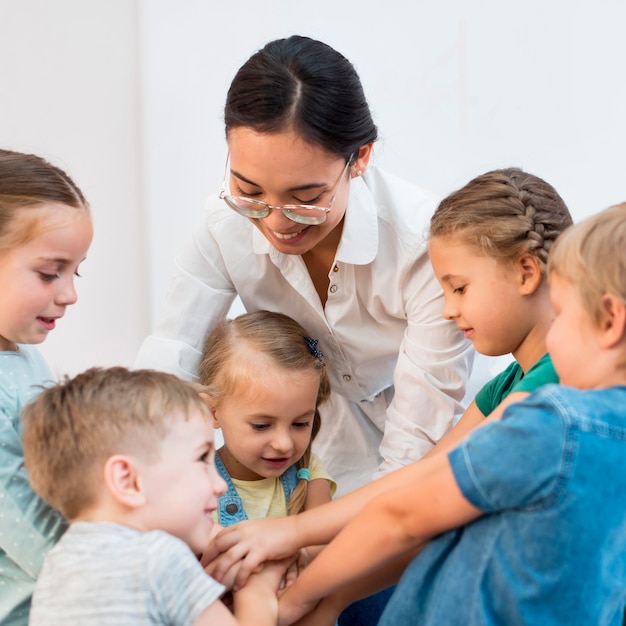 Kostenloses Foto die lehrerin legt ihre hände mit ihren schülern zusammen