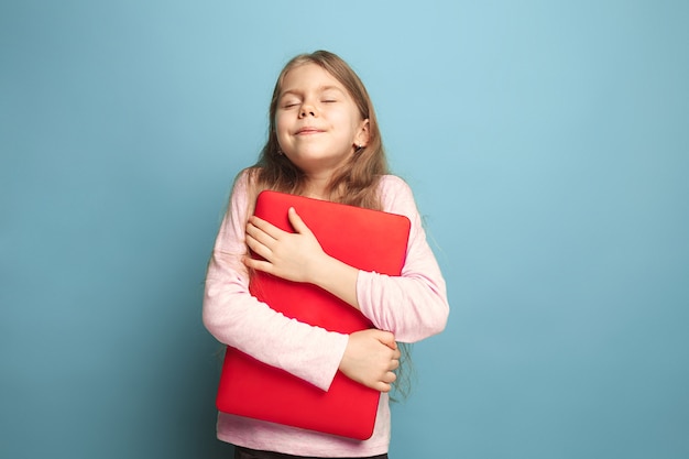 Die Liebe zum Computer. Teenie-Mädchen mit Notizbuch auf einem Blau.