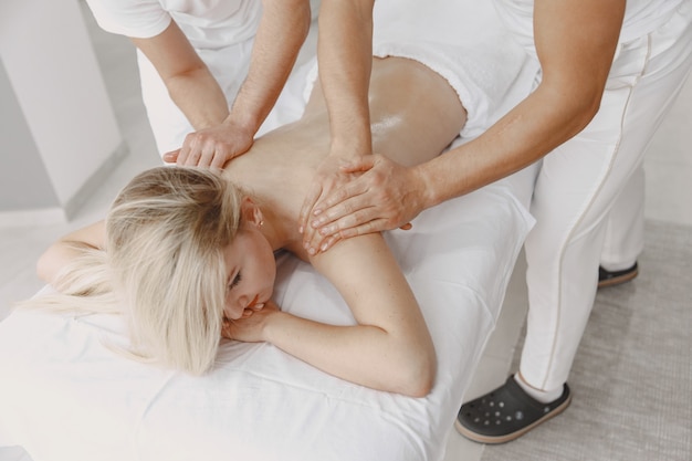 Die Massage mit vier Händen. Konzept der Gesundheitsversorgung und der weiblichen Schönheit. Zwei Masseurinnen machen eine Doppelmassage eines Mädchens. Frau in einem Spa-Salon.