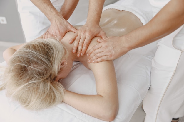 Die Massage mit vier Händen. Konzept der Gesundheitsversorgung und der weiblichen Schönheit. Zwei Masseurinnen machen eine Doppelmassage eines Mädchens. Frau in einem Spa-Salon.