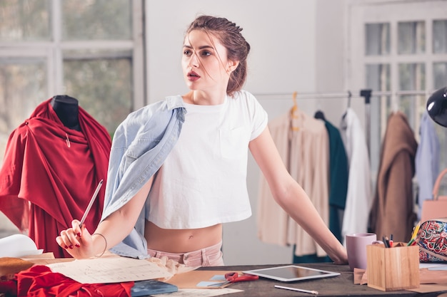 Kostenloses Foto die modedesignerin, die im studio arbeitet, sitzt auf dem schreibtisch