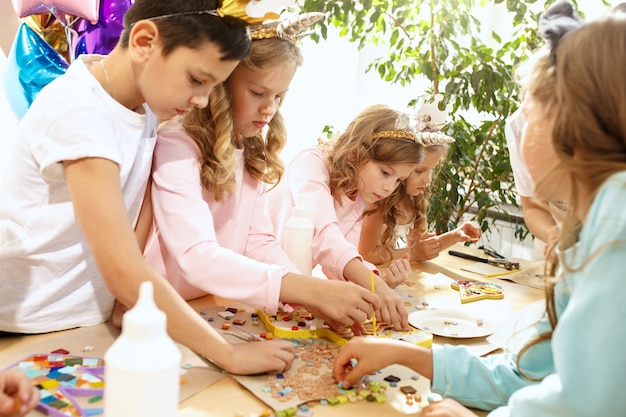 Die Mosaik-Puzzle-Kunst für Kinder, kreatives Spiel für Kinder. Die Hände spielen Mosaik am Tisch. Bunte mehrfarbige Details schließen. Kreativität, Kinderentwicklung und Lernkonzept