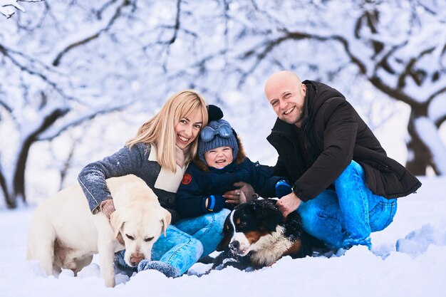 Die Mutter, der Vater, der Sohn und die Hunde, die auf dem Schnee sitzen