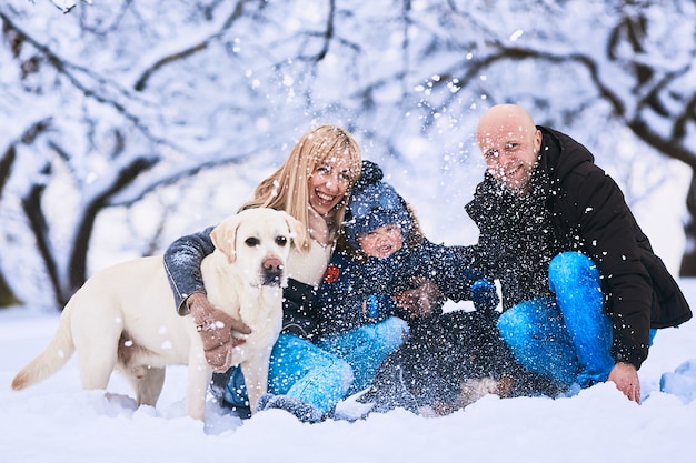 Die Mutter, der Vater, der Sohn und die Hunde, die auf dem Schnee sitzen