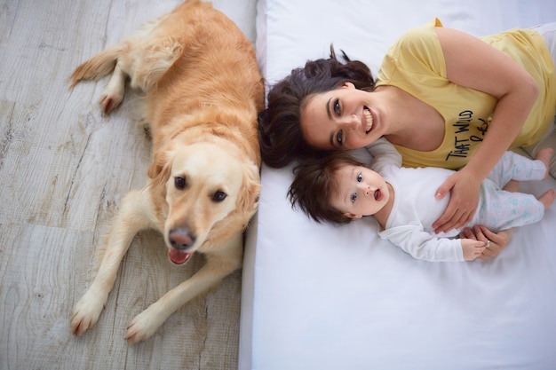 Die Mutter mit der Tochter liegt auf dem Bett und dem Hund, der nahe Bett sitzt